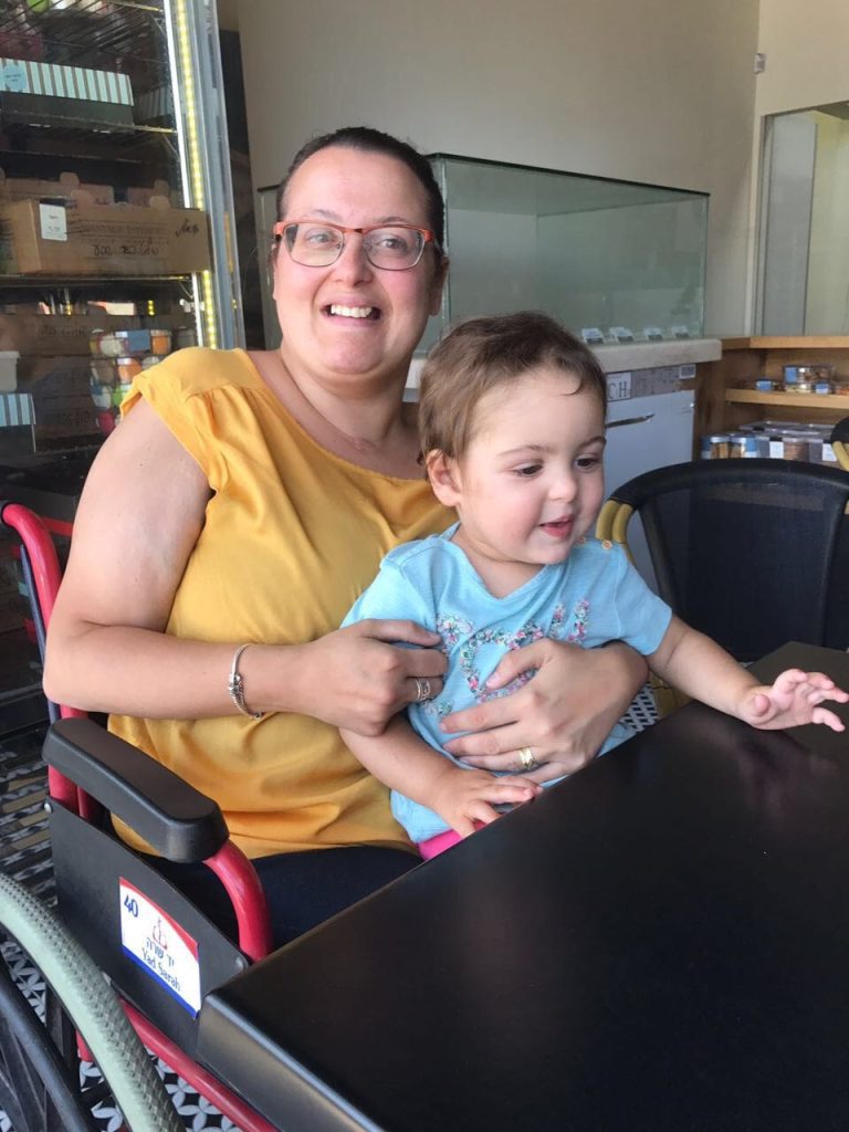 אישה בכסא גלגלים מחזיקה ילדה Women in a wheelchair holding a child